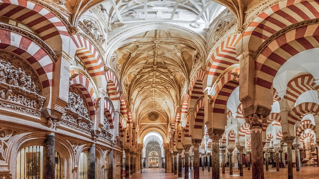 Interiors of the Cordoba Mosque-Cathedral prayer hall with red and white arches.