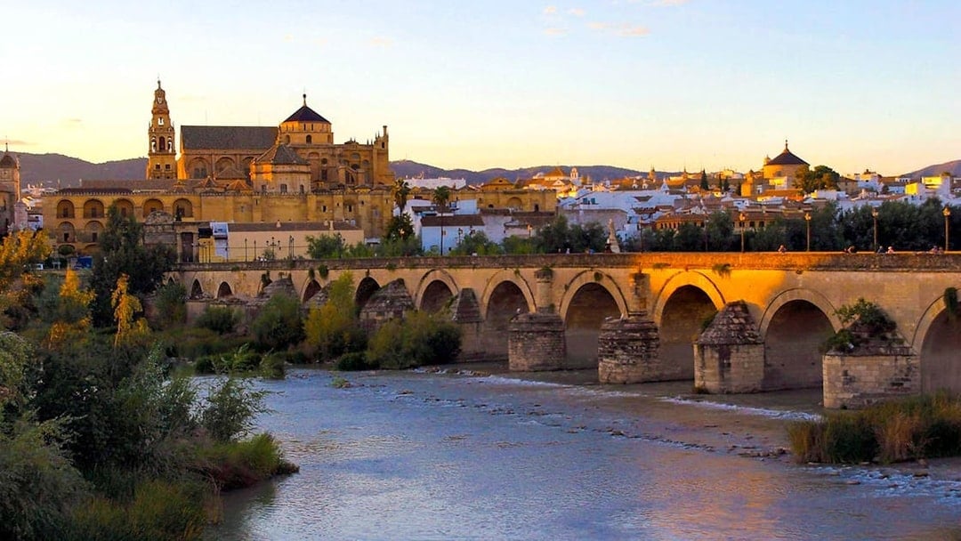 Mosque-Cathedral of Córdoba and Roman Bridge at sunset, view from the Guadalquivir River.