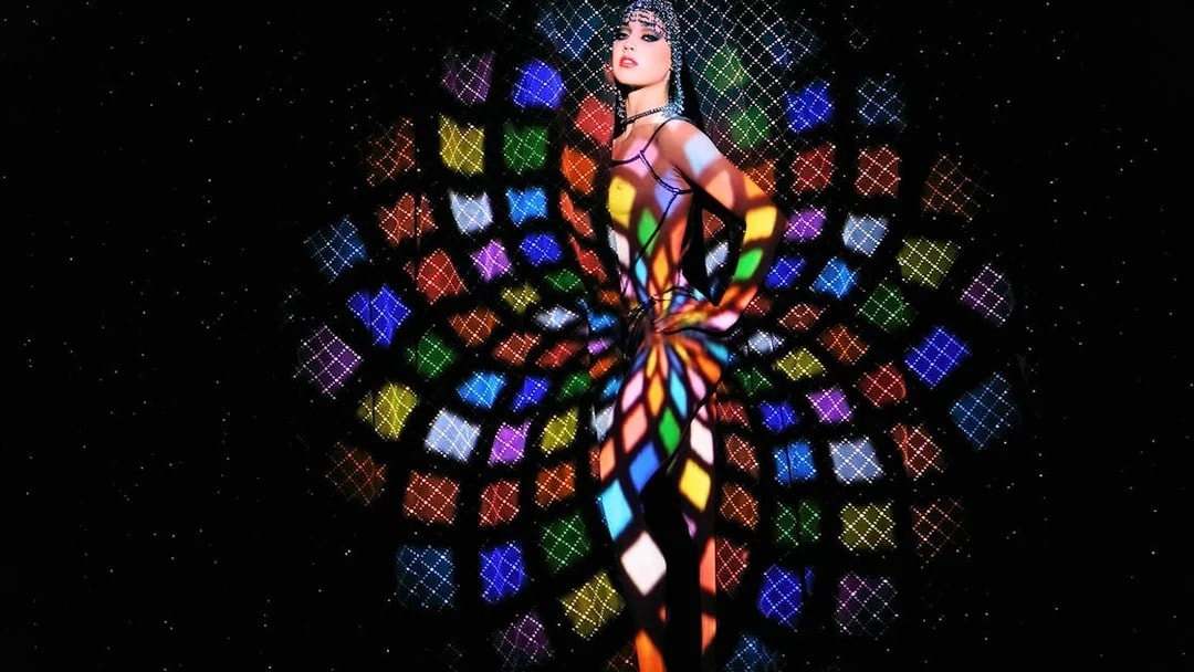 Performer at Crazy Horse Show with colorful light patterns in Paris.