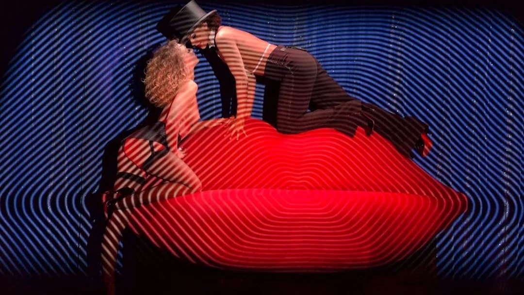 Performers on stage at Crazy Horse show in Paris, with vibrant lighting effects.