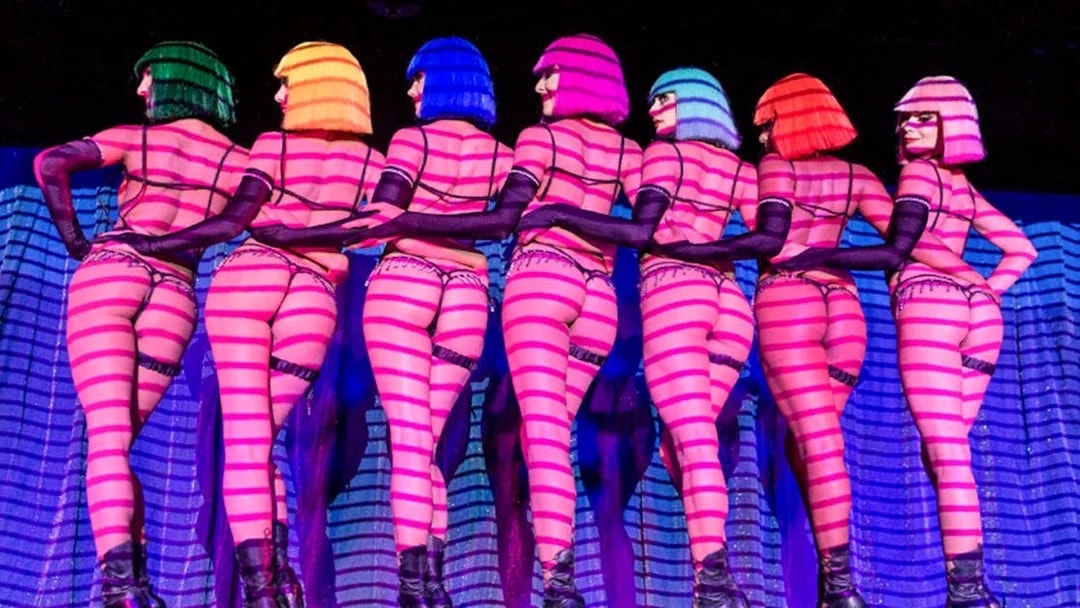 Dancers in colorful wigs performing at Crazy Horse show in Paris.