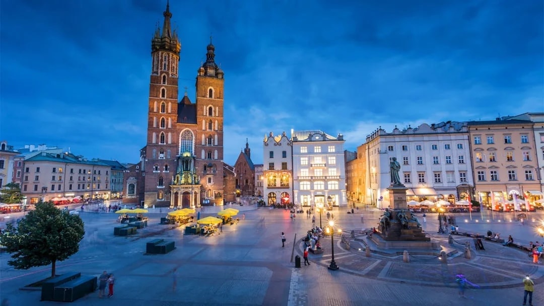 St. Mary's Basilica and Adam Mickiewicz Monument in Krakow's Main Square at dusk.