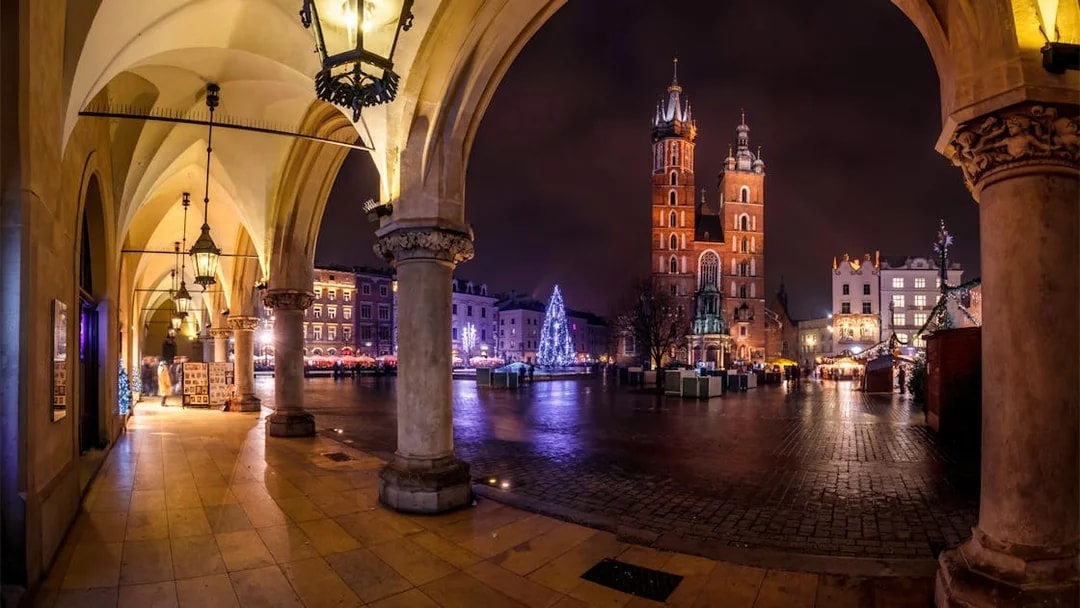 Krakow's Main Square at night with St. Mary's Basilica and festive lights.