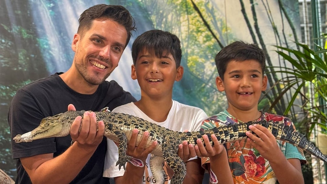 Visitors holding a young crocodile at Crocodile Adventureland Langkawi.