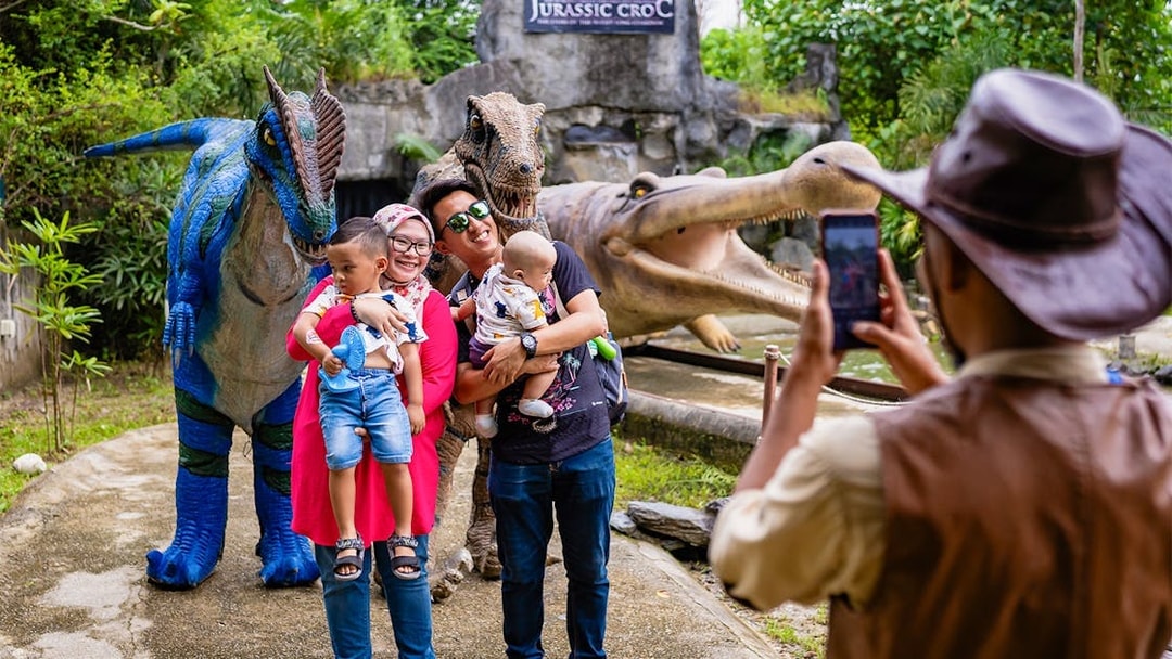 Family posing with dinosaur statues at Crocodile Adventureland Langkawi.