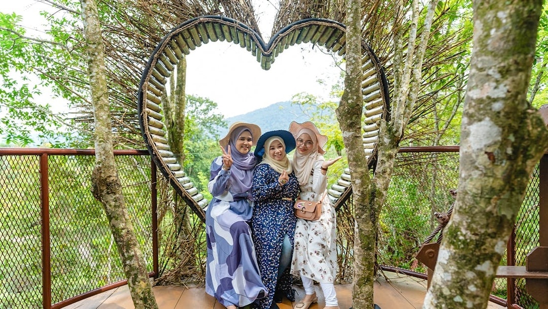Three people posing in front of a heart-shaped structure at Crocodile Adventureland Langkawi.