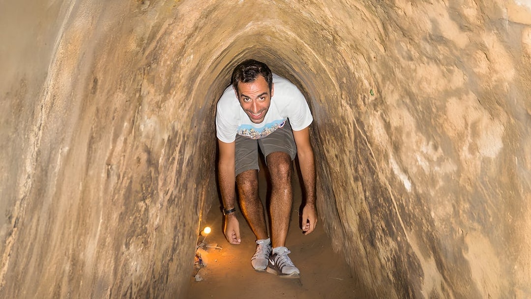Person exploring narrow Cu Chi Tunnels on half-day tour in Vietnam.