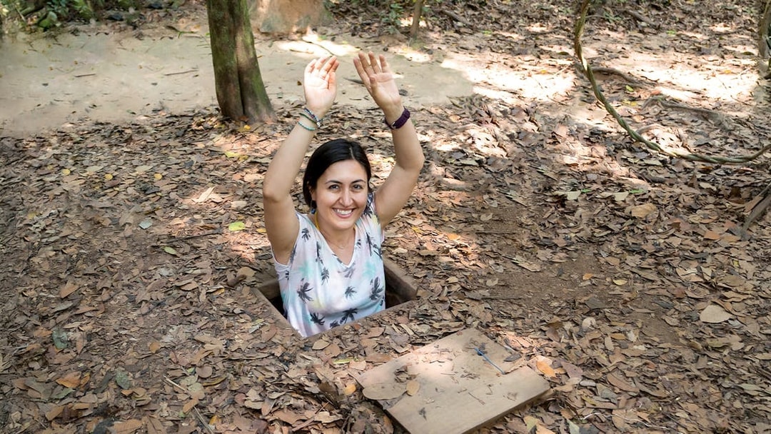 Woman emerging from a tunnel entrance at Cu Chi Tunnels, Vietnam.