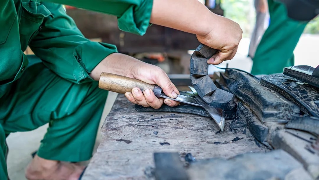 Crafting rubber slippers from car tire at Cu Chi tunnel, Vietnam.