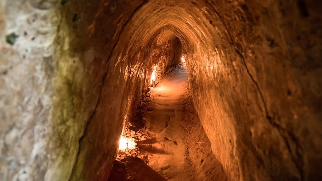 Narrow passage inside Cu Chi Tunnels, Vietnam, dimly lit with warm lights.