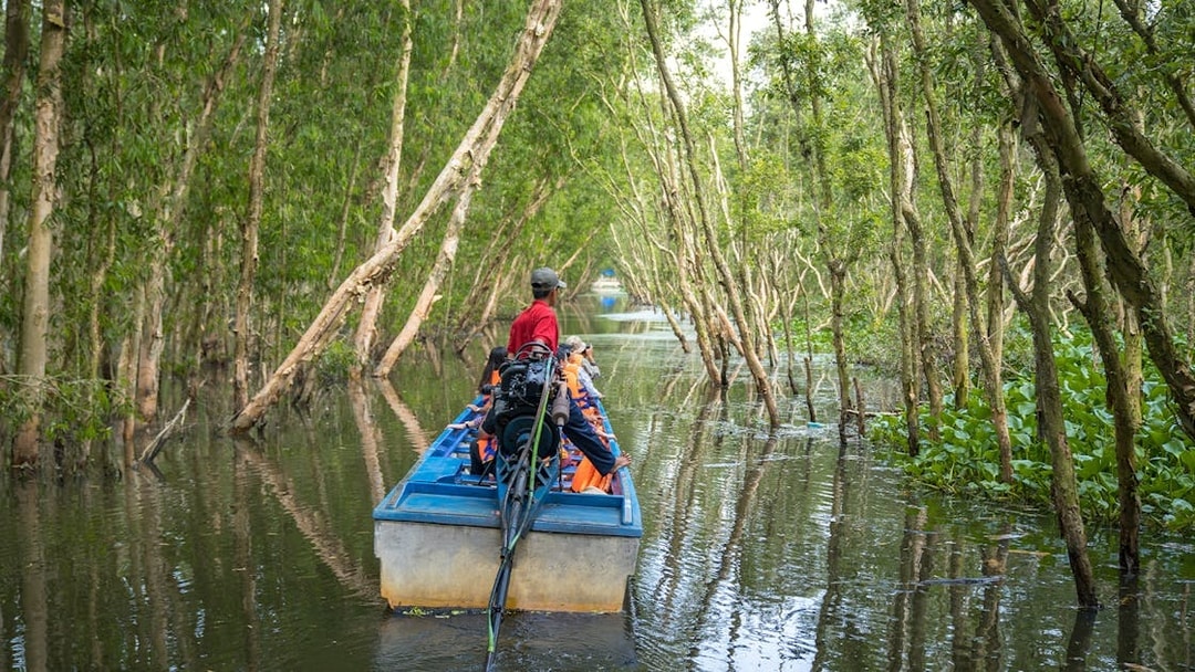 Motorboat navigating through lush trees in Mekong Delta.