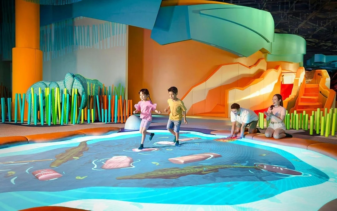Children playing on interactive water-themed floor at Curiosity Cove Grassland Water Hole.