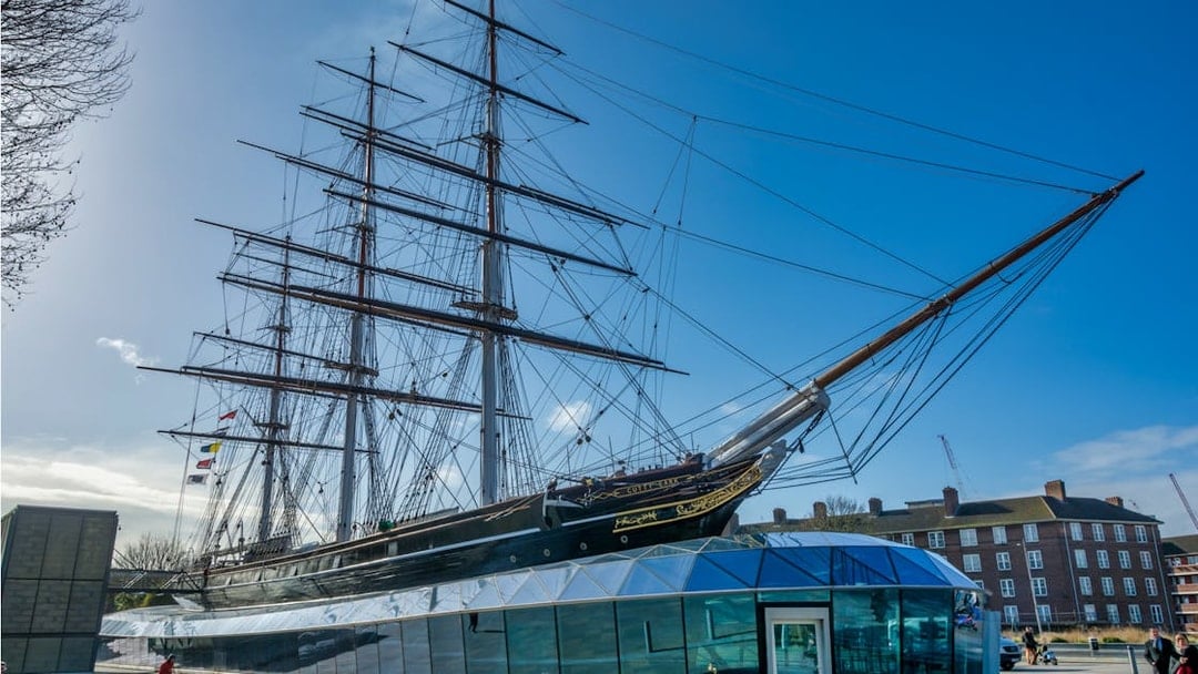 Cutty Sark ship in Greenwich, London, with modern glass entrance below.