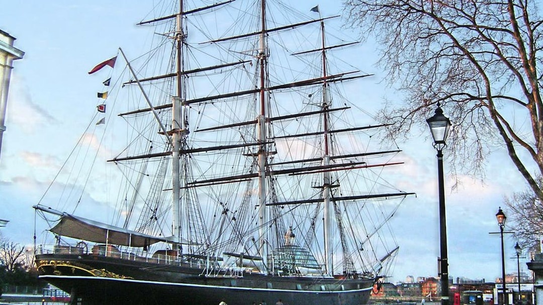 Cutty Sark ship docked in Greenwich, London, with visitors walking nearby.