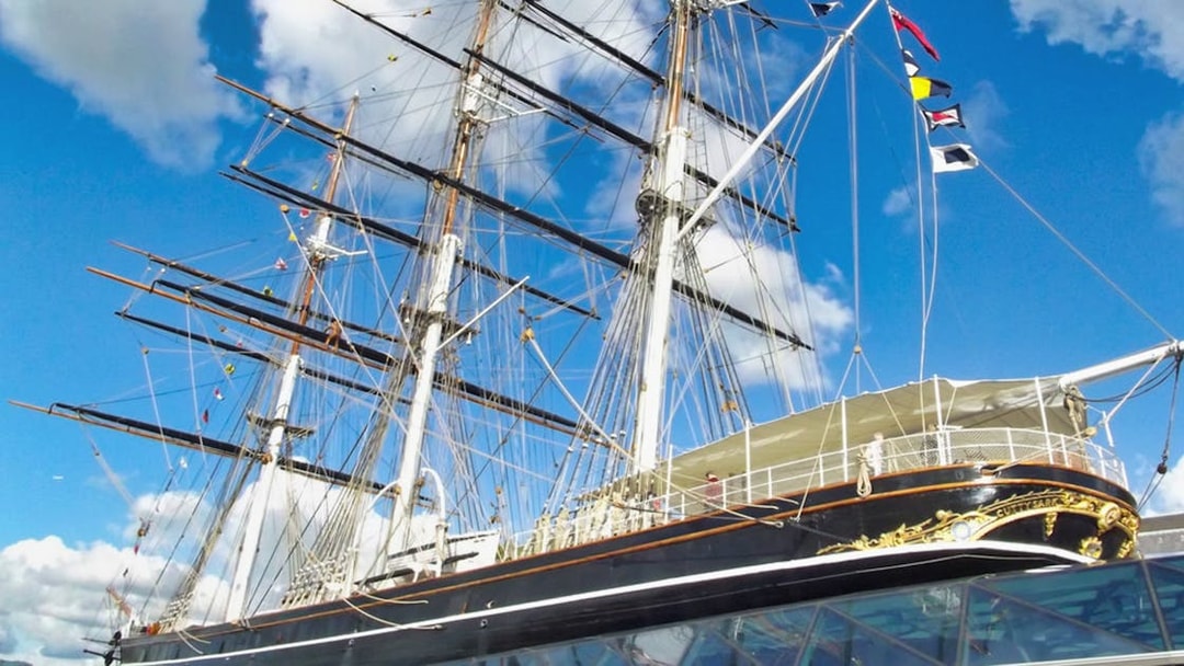 Cutty Sark ship with masts and rigging against a blue sky in Greenwich, London.