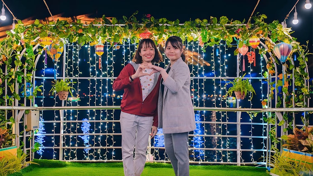 Couple on My Xuan Cruise, Han River, surrounded by lights and greenery at night.