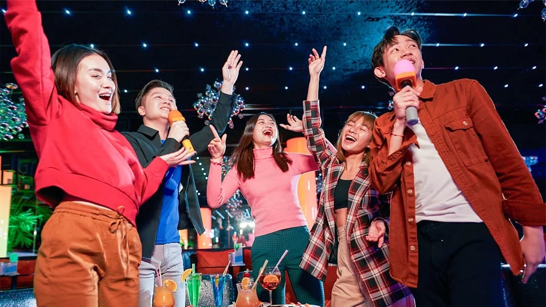 Group enjoying karaoke and drinks at a vibrant indoor venue in Singapore.
