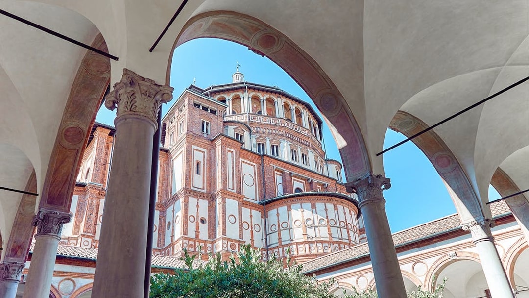 Santa Maria delle Grazie exterior, Milan, Italy, viewed through arches on a guided tour of Da Vinci's Last Supper.