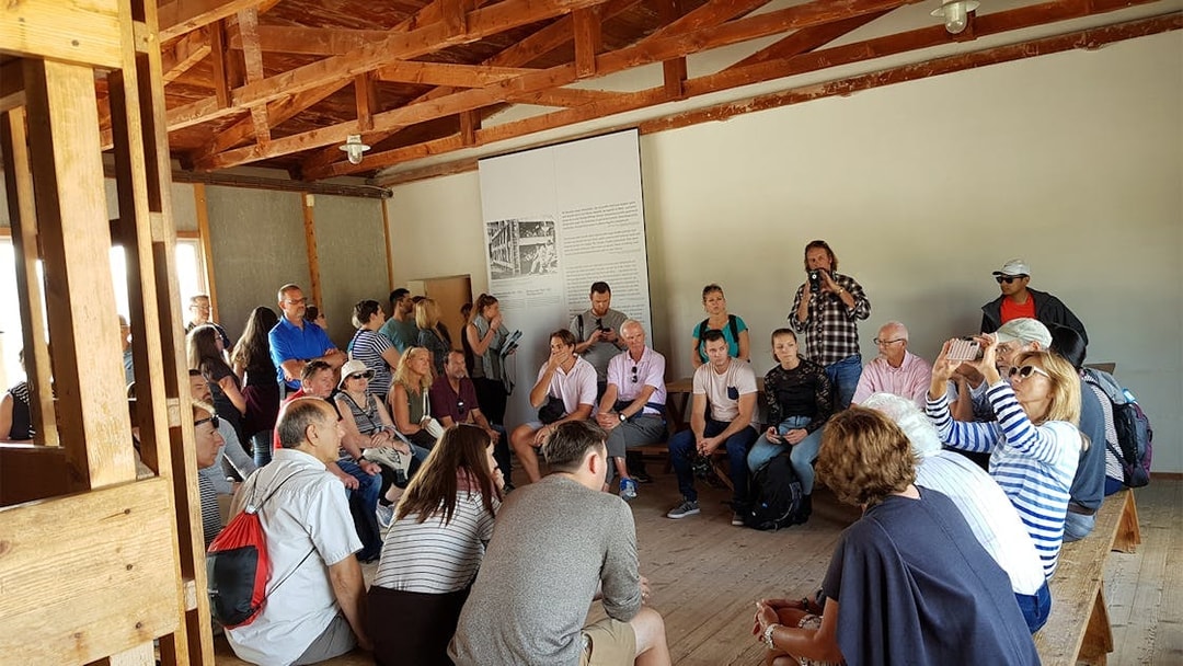 Visitors listening to a guide at Dachau Concentration Camp Memorial Site.
