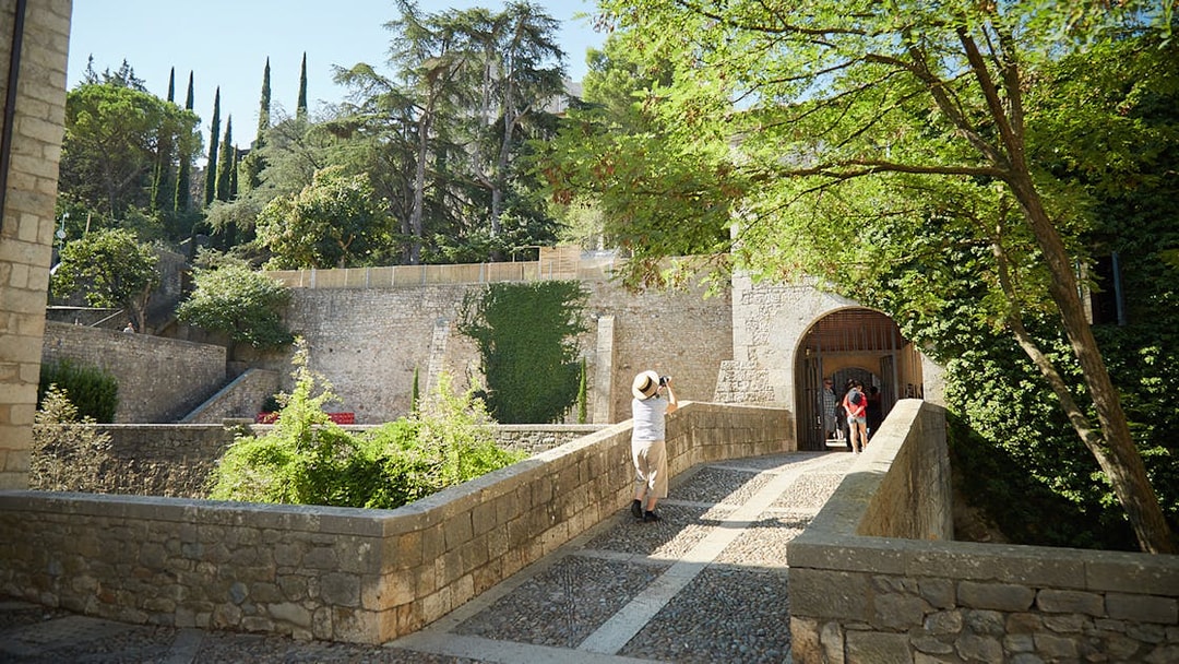 Visitor exploring historic stone walls in Girona, Spain.