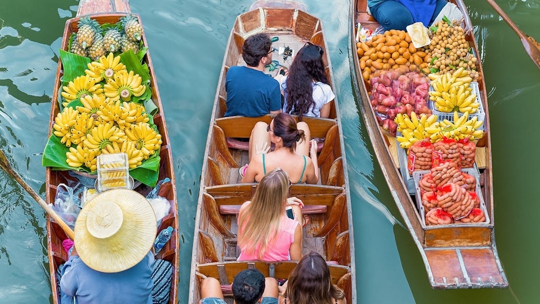 Boats with tourists and vendors selling fruit at Damnoen Saduak Floating Market, Thailand.