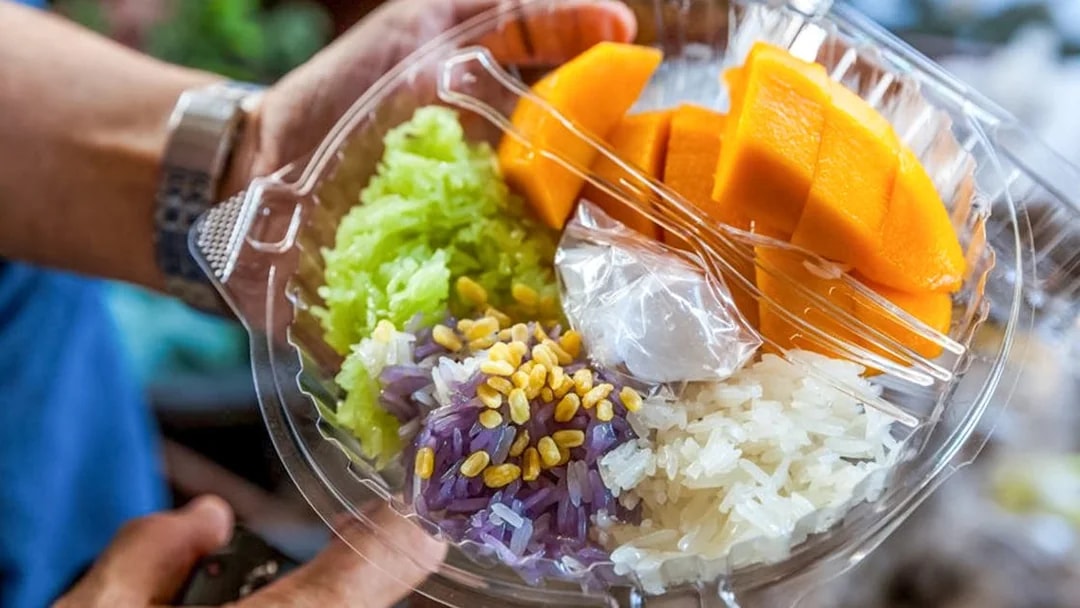 Mango sticky rice with colorful rice varieties and coconut sauce, traditional Thai dessert.