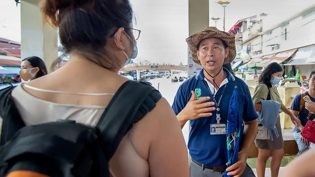 Guide explaining to tourists in Amphawa market area.