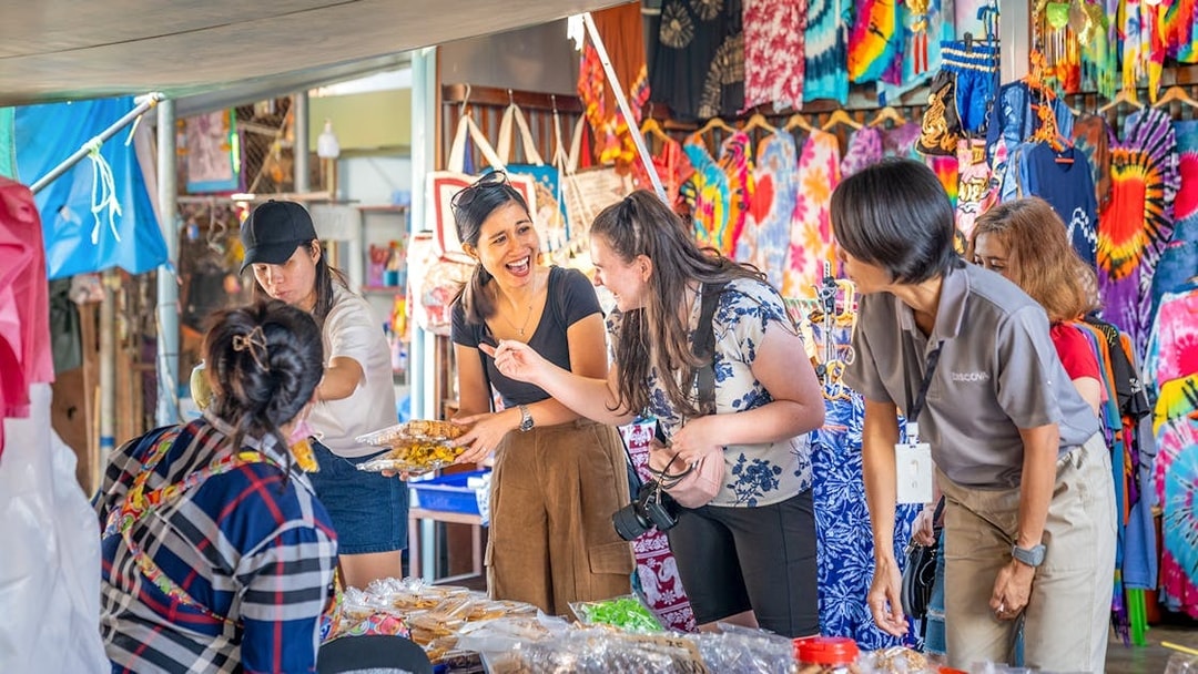 Tourists exploring food stalls at Damnoen Saduak Floating Market, Thailand.