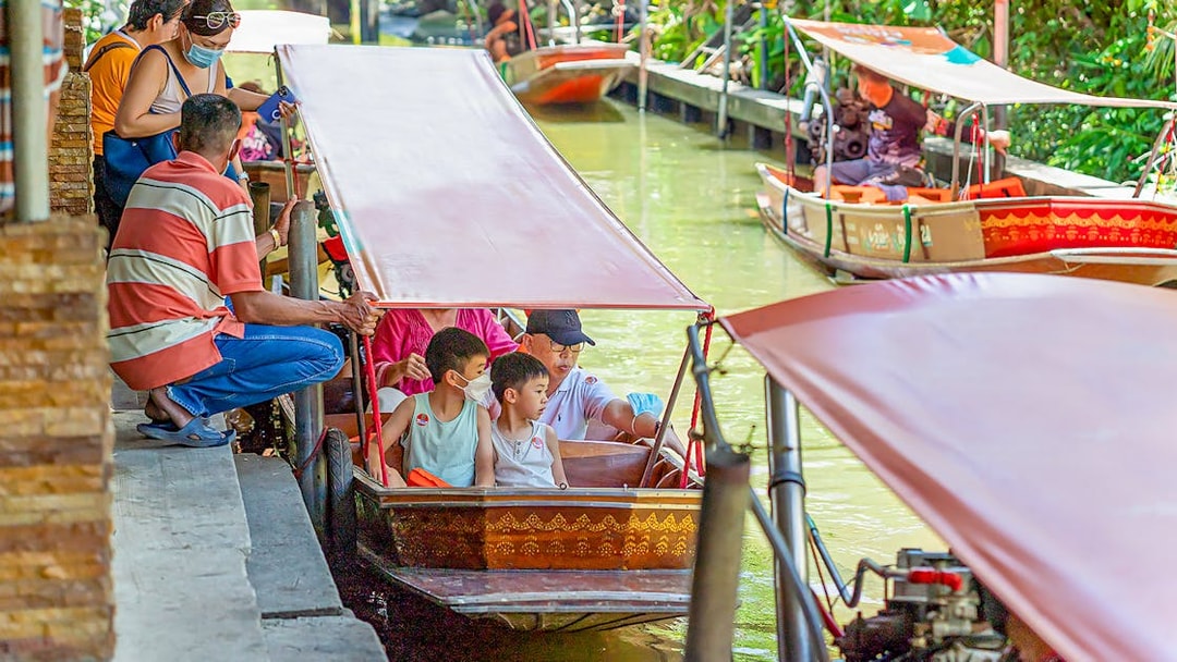 Visitors on a boat tour at Damnoen Saduak Floating Market, Thailand.