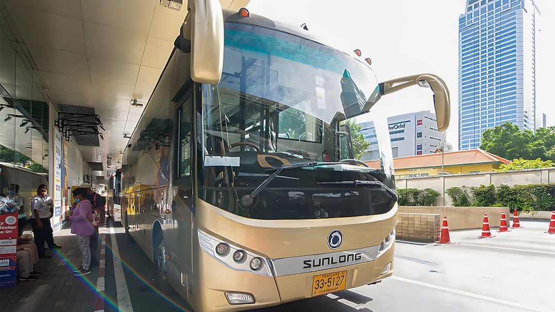 Tour bus parked at a station, ready for the Damnoen Saduak Floating Market & Maeklong Railway Market tour.