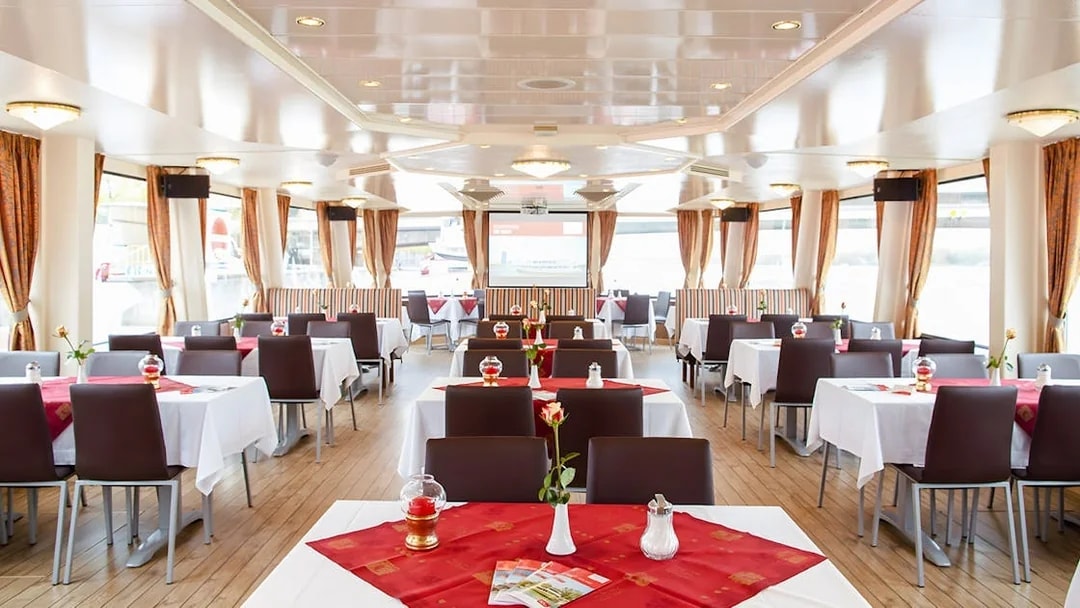 Interior of a Vienna sightseeing cruise ship with dining tables and large windows.