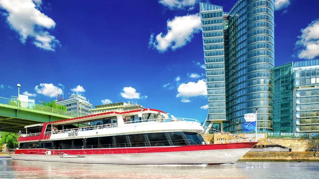 MS Wien ship on Danube Canal, Vienna, with UNIQA Tower in background.