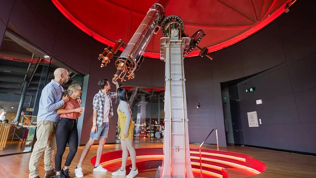 Guests examining telescope at Dark Sky Indoor Cultural Astronomy Experience.