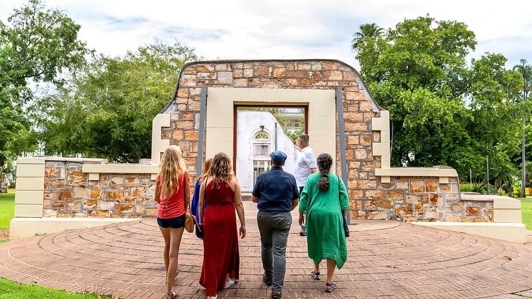 Group walking through historic stone archway on art tour.