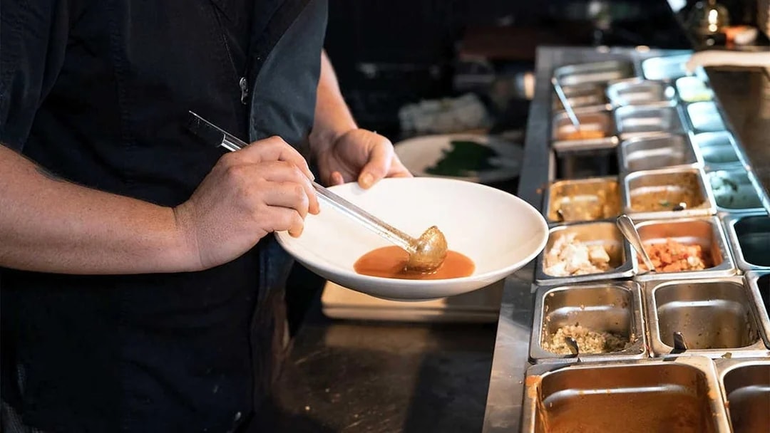 Chef preparing gourmet dish with sauce during 3.5-hour lunch or dinner art tour.