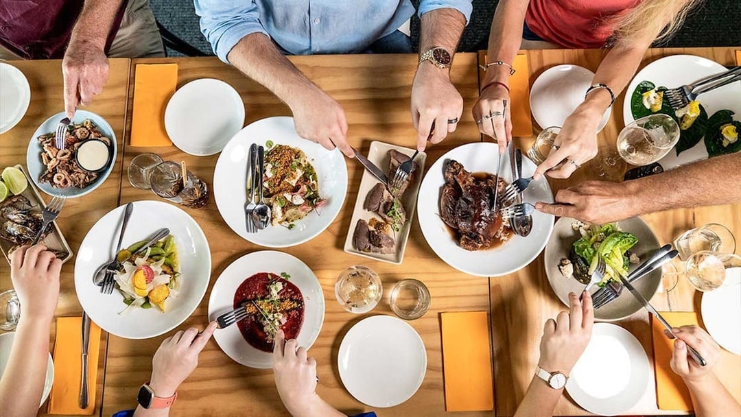 Gourmet dishes being shared at a communal table during a 3.5-hour lunch or dinner art tour.