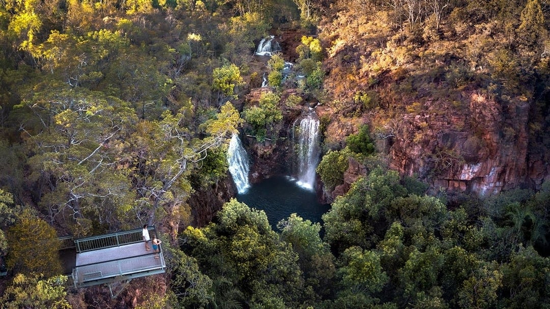 Litchfield National Park waterfall view from lookout platform, surrounded by lush greenery.