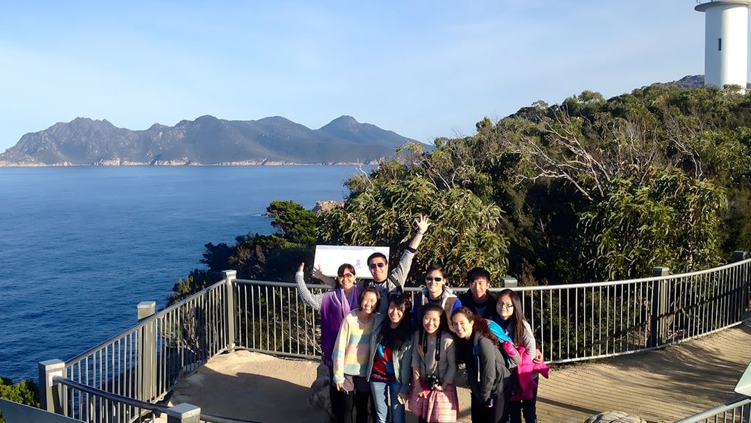 Group at Wineglass Bay lookout with ocean and mountains, Launceston to Hobart tour.