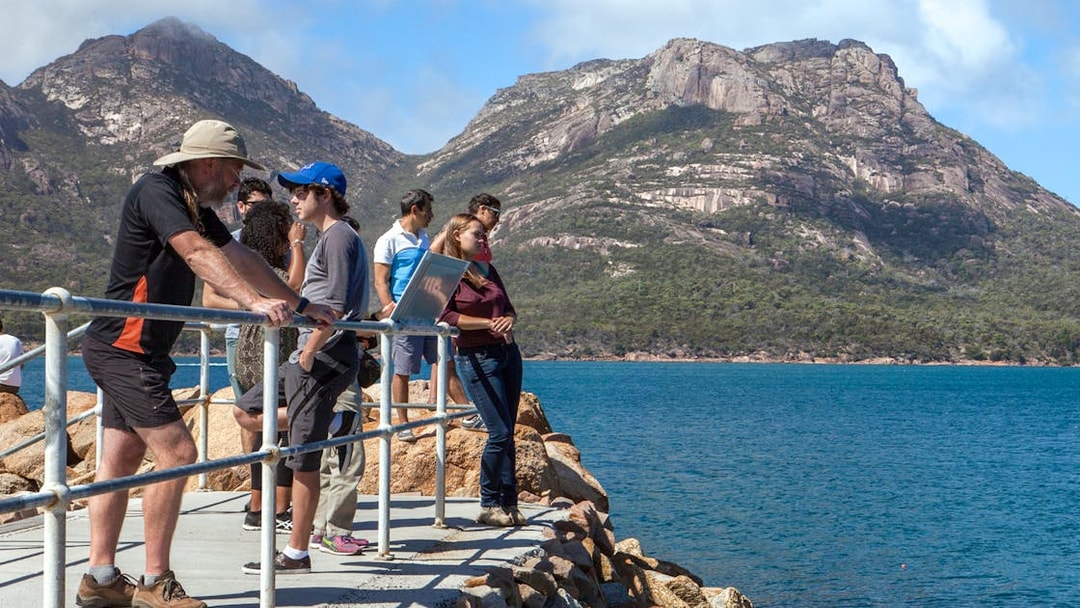 Visitors enjoying the view of Wineglass Bay with mountains in the background, Tasmania.