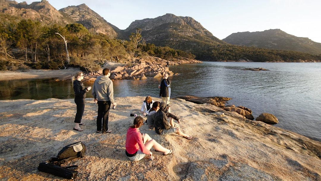 Group enjoying the view at Wineglass Bay, Tasmania, with mountains in the background.