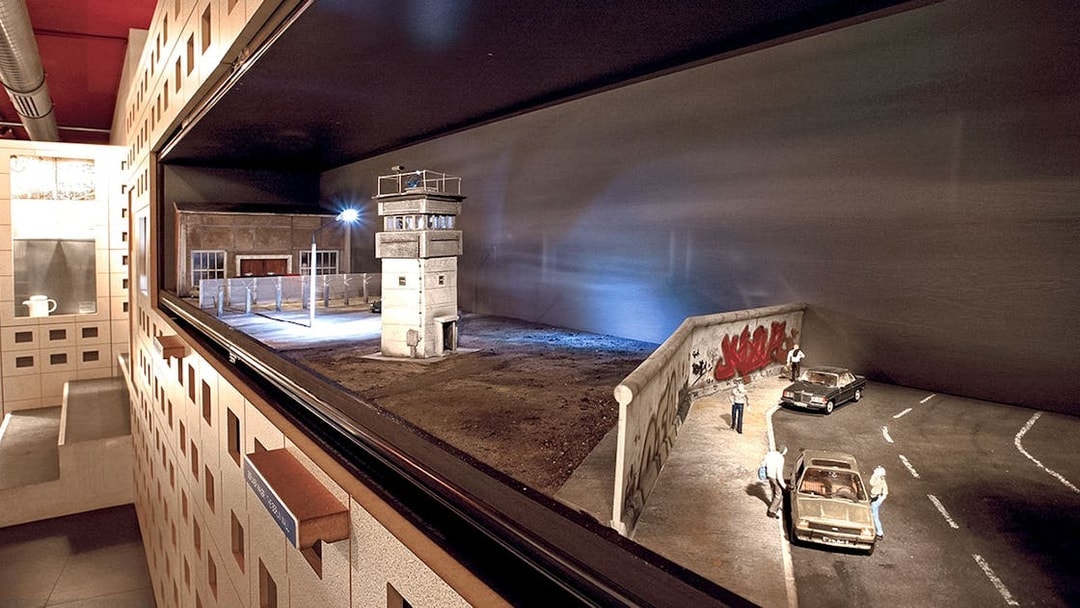 DDR Museum Berlin exhibit featuring Berlin Wall and guard tower model.