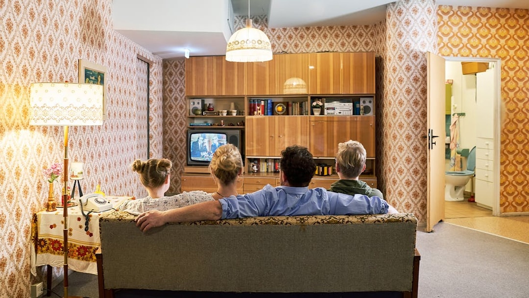 Family watching TV in a 1970s-style living room at DDR Museum German Apartment.