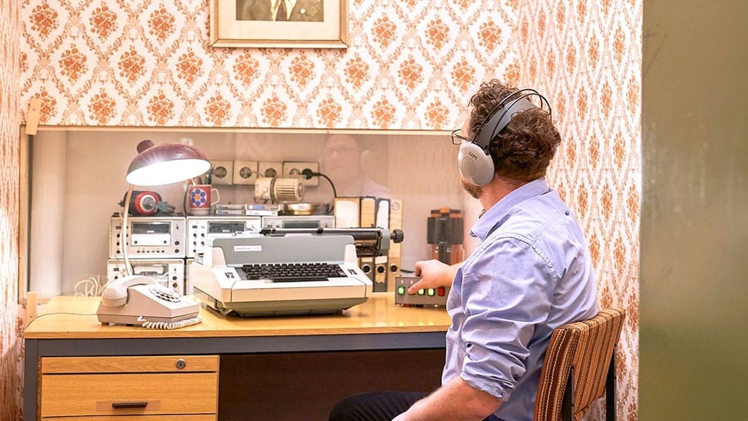 Man using vintage typewriter and equipment at DDR Museum Berlin.