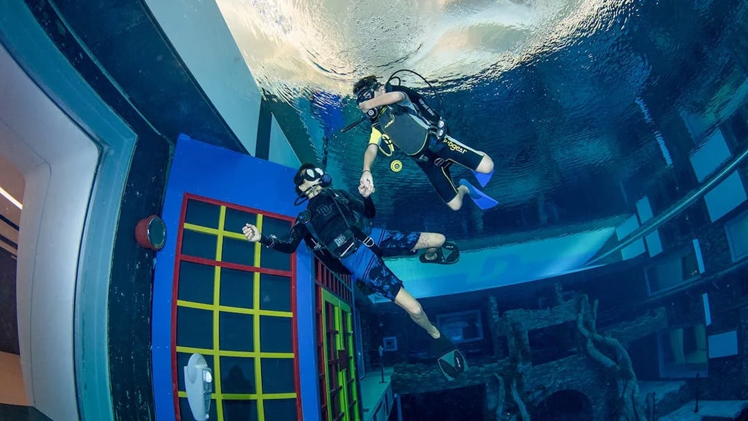 Scuba divers exploring underwater structures at Deep Dive Dubai.
