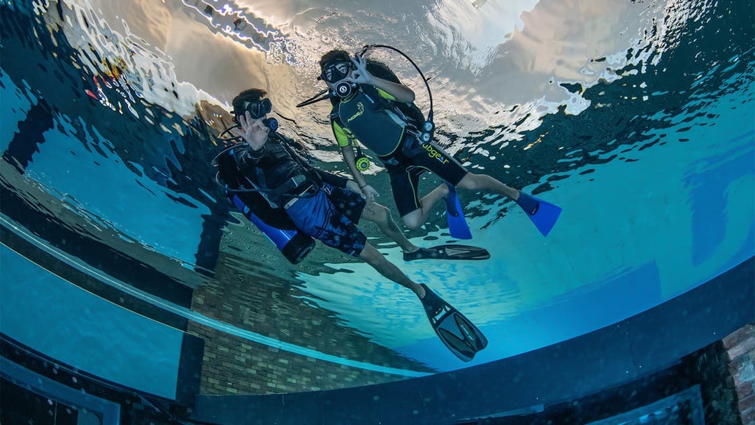 Scuba divers exploring Deep Dive Dubai pool.