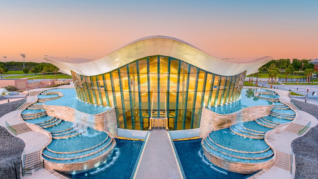 Deep Dive Dubai building with cascading pools at sunset.