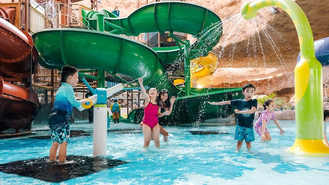 Children playing near a water slide in an indoor water park in Doha.