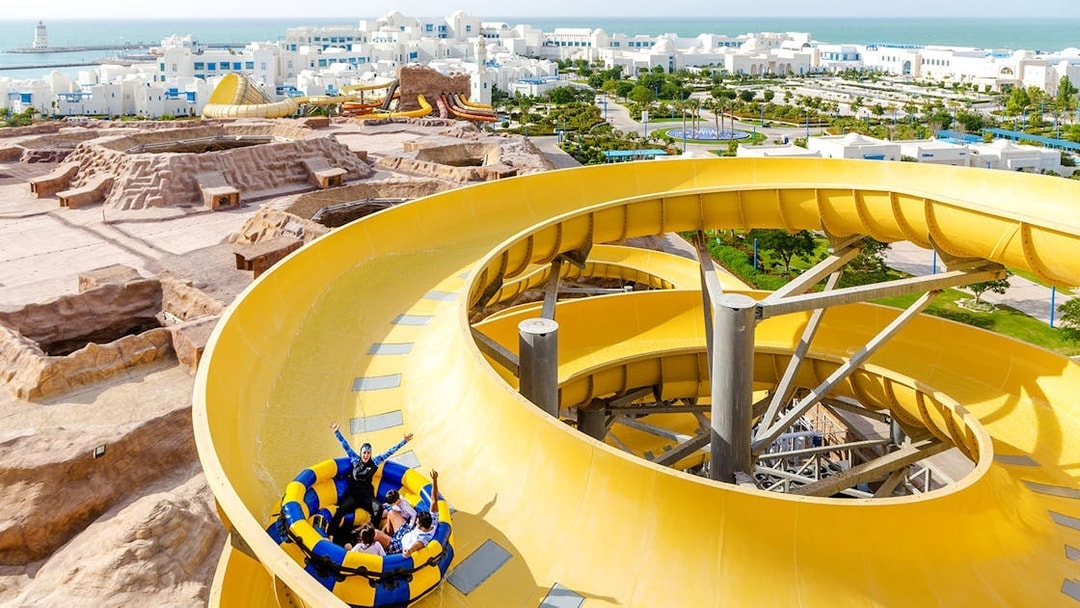 Group enjoying a yellow water slide at a theme park in Doha.