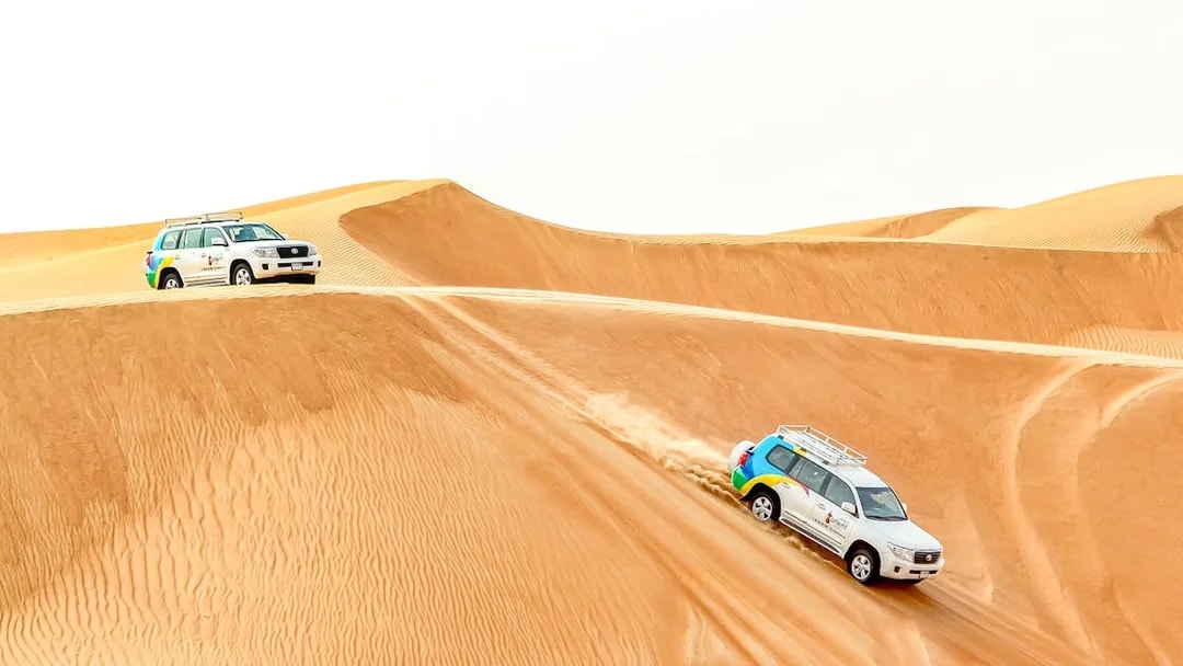 SUVs driving on sand dunes during a desert safari tour.