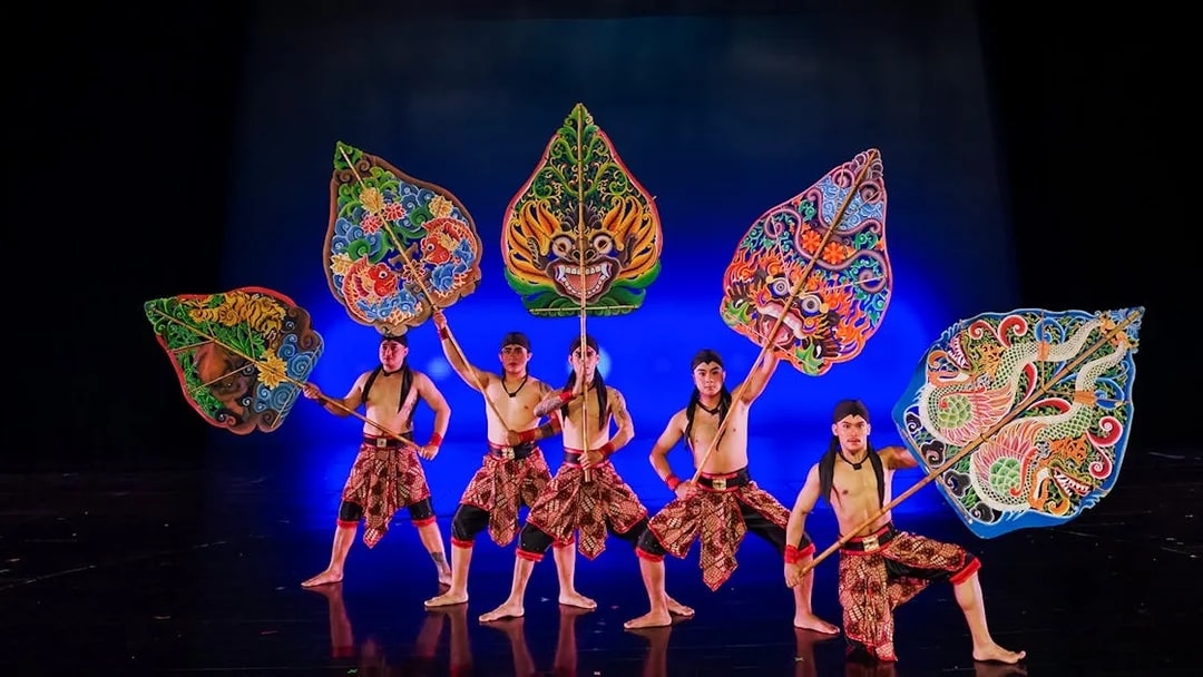 Performers with colorful shields on stage during the Devdan Show in Bali.